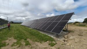 A man from Ernest Energy walking beside a row of solar panels installed on a farm in Southland